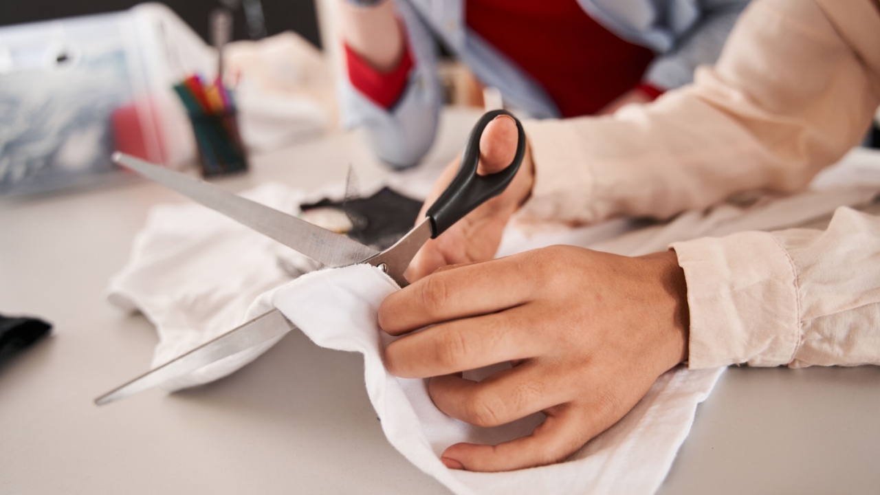 Man and woman colleagues cutting t shirt with scissors while creating something great