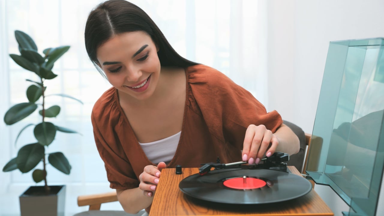Happy young woman using turntable at home