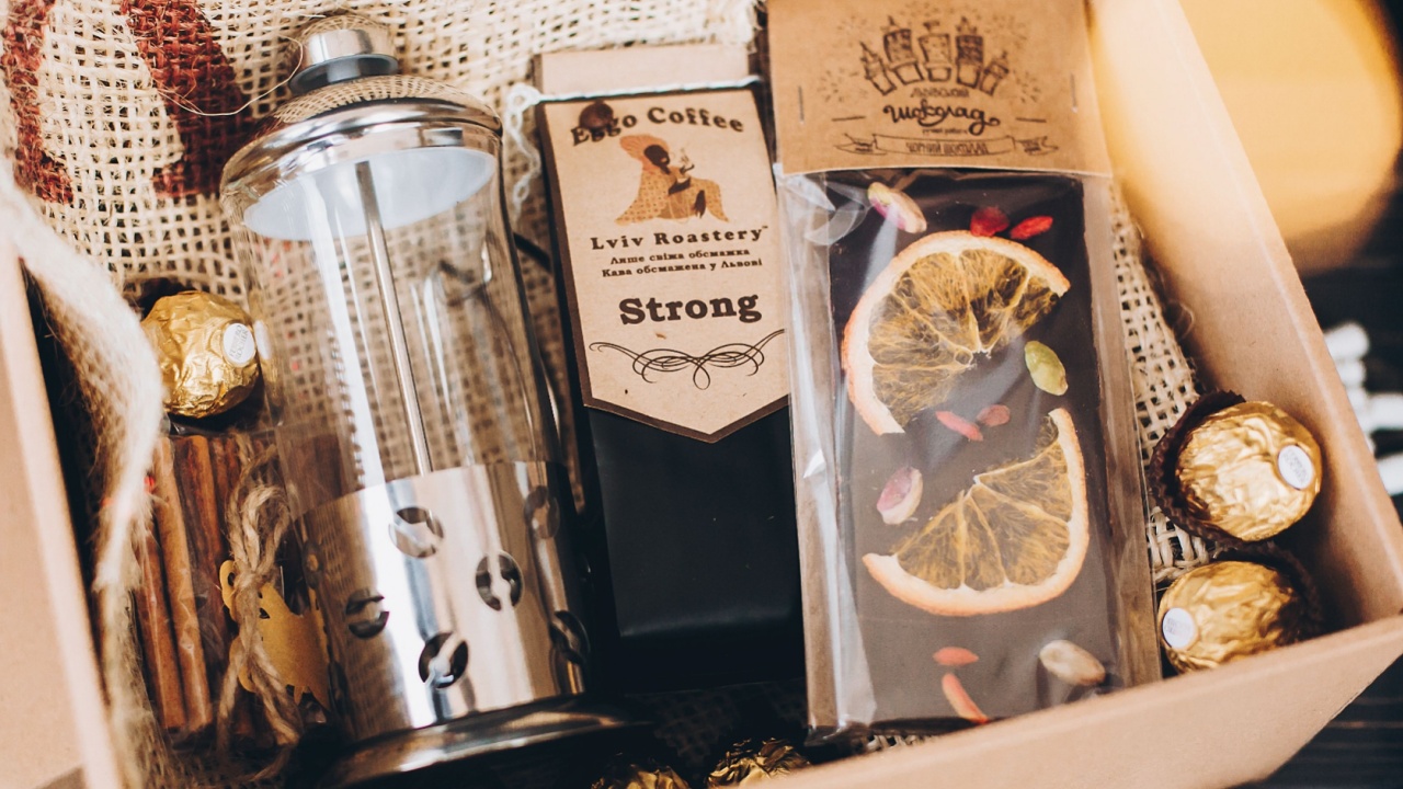 Lviv, Ukraine - December 1, 2017: Roasted Coffee, french press and chocolate candy on straw in lights. Stylish coffee gift box for christmas, new year, birthday, fathers or mothers day