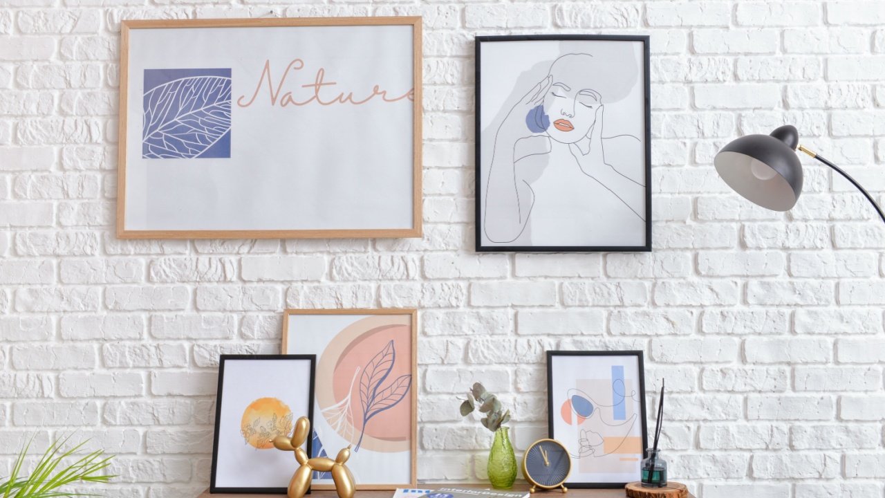 Table with decor and pictures hanging on brick wall