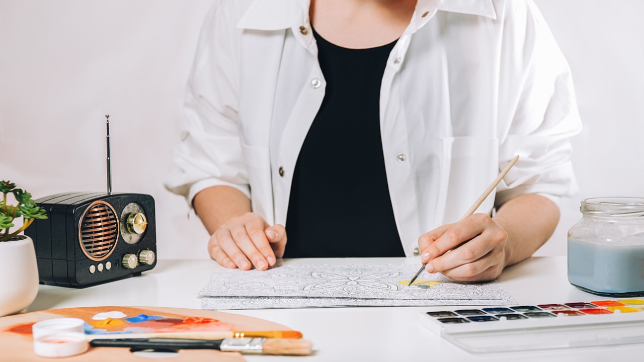 Art therapy or self expression for adults. Young woman is coloring page anti stress book, mental wellbeing and creativity inspiration expression concept.