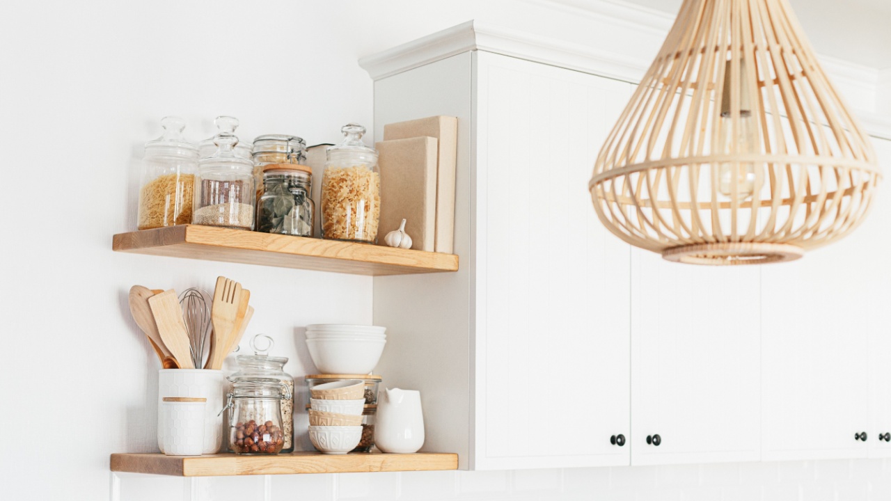 Kitchen shelves with various white ceramic, glass jars, cookbook. Open shelves in the kitchen. Kitchen interior open shelving ideas. Eco friendly kitchen, zero waste home concept
