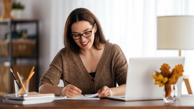 Happy young woman working online, watching webinar, podcast on laptop, having remote conversation at home.