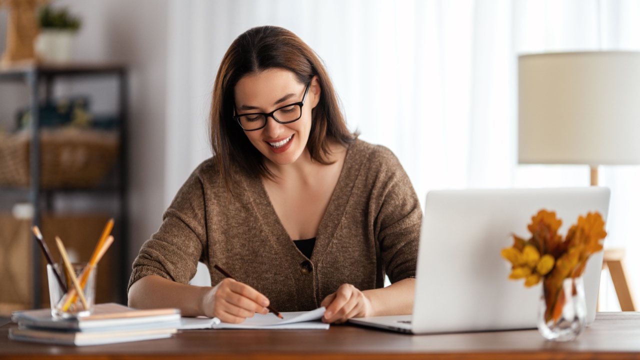 Happy young woman working online, watching webinar, podcast on laptop, having remote conversation at home.