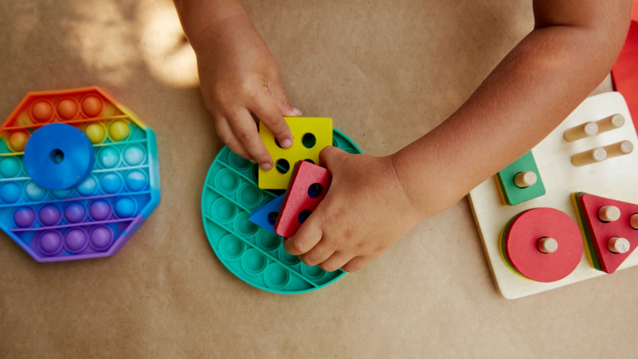 Toddler plays with colorful antistress sensory toy fidget push pop it. Trendy pop it toy for the development of fine motor skills. Rainbow sensory fidget. New trendy silicone toy and wooden eco toys