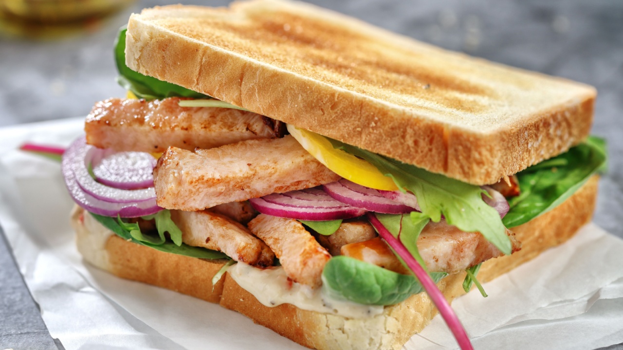 Appetizing toast with chicken chunks and salad on table.