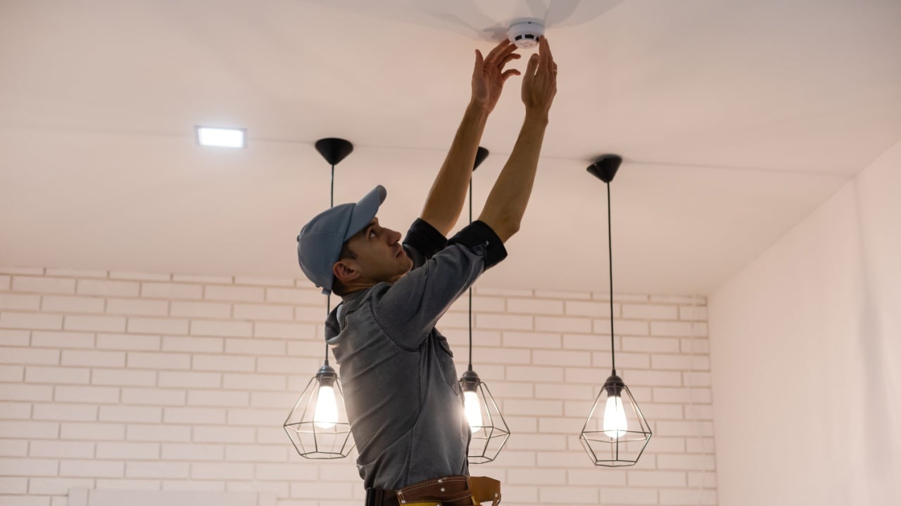 Handyman installing a smoke detector on the ceiling