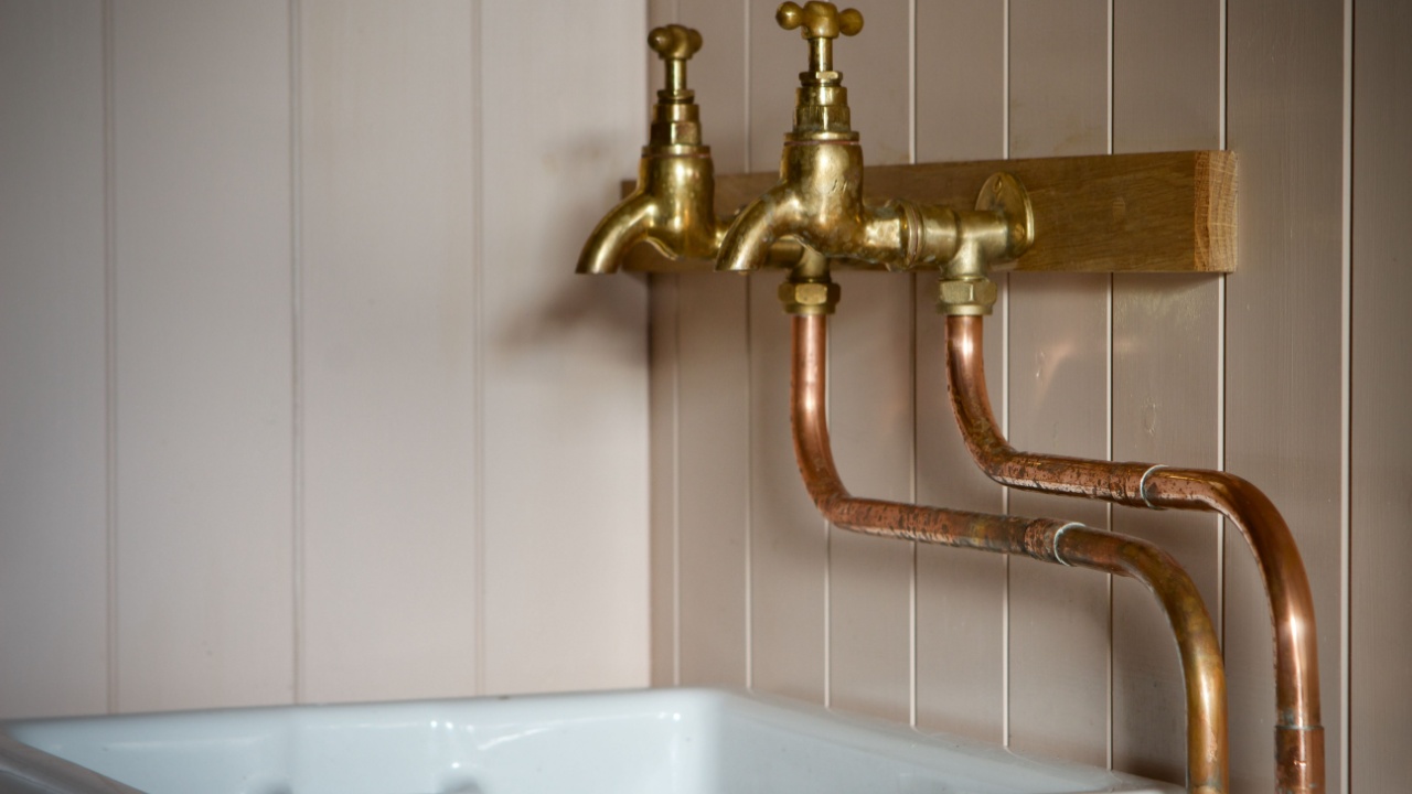 Brass faucets wall mounted over a white butler sink