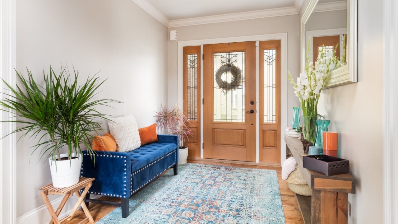 CHICAGO, IL, USA -SEPTEMBER 18, 2020: A renovated foyer with hardwood floors, a wood door with frosted glass, and colorful furniture to fill the space.