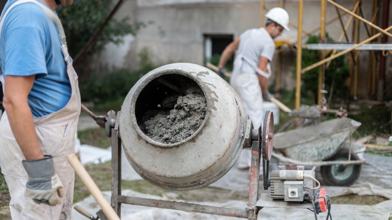 Labore worker operating concrete cement mixer at construction site.