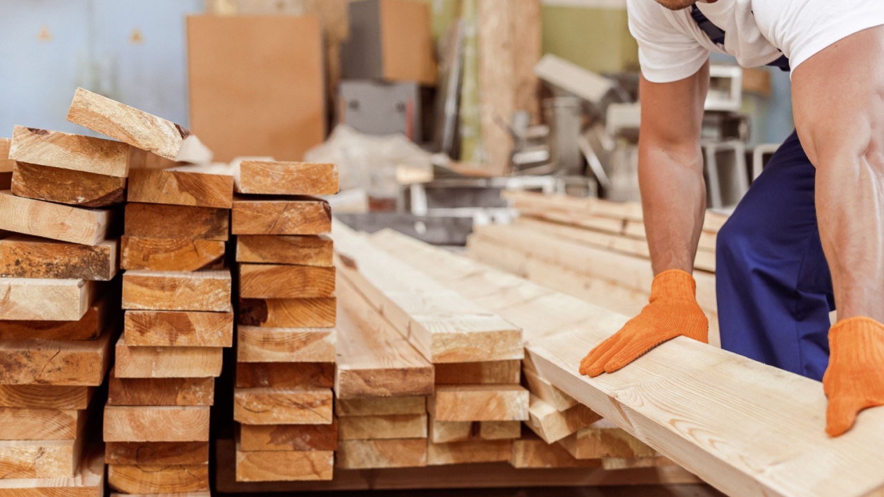 Handsome male builder holding wooden plank at construction site