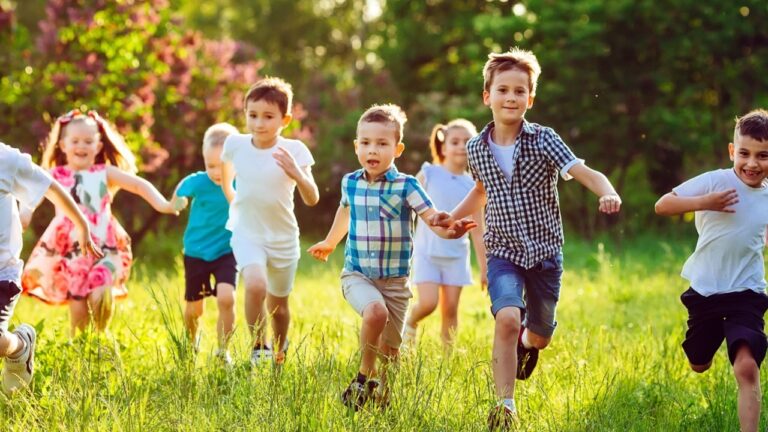A group of happy children of boys and girls run in the Park on the grass on a Sunny summer day