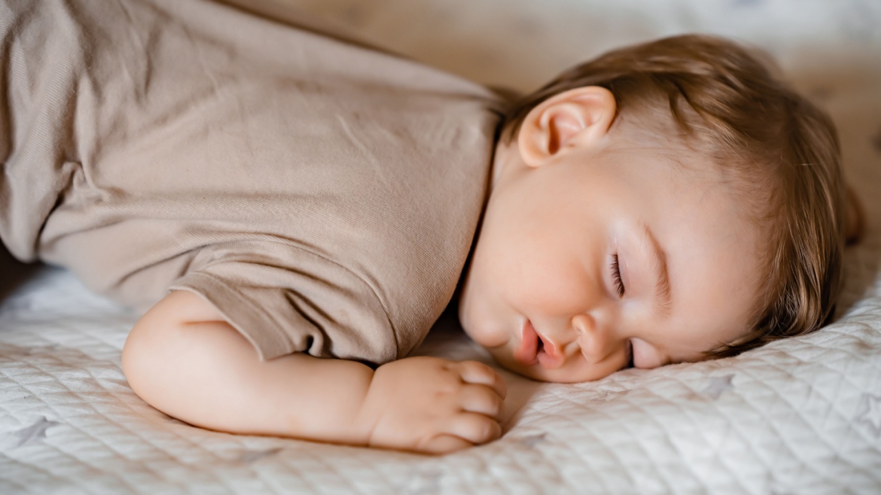 Portrait of a funny baby sleeping on his stomach on the bed at home. Close up. High quality photo