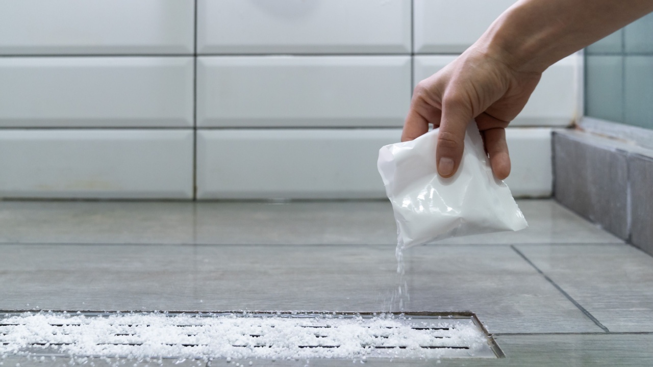 Closeup of woman hand pouring pipe cleaner granules. Removal of blockage in the shower of a special remedy with powder. Clean the blockages in the bathroom with chemicals.