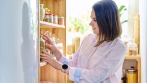Young woman in kitchen with containers jars of food