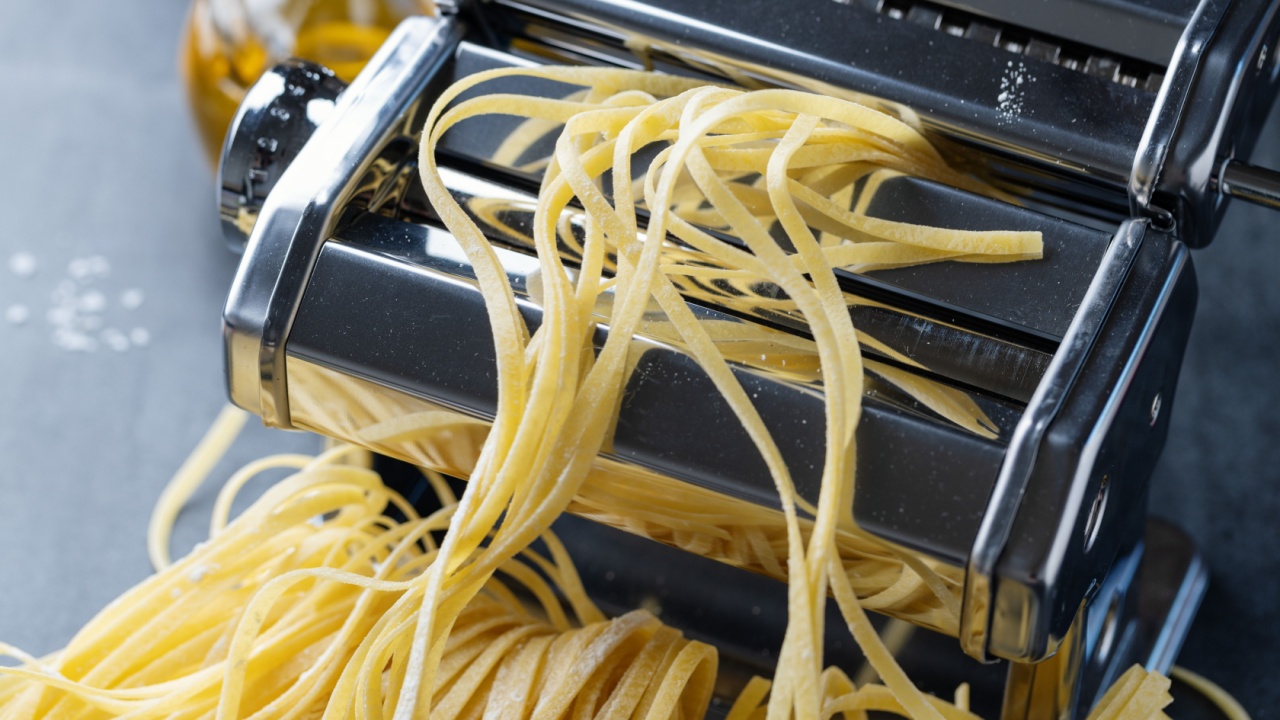 Homemade pasta in pasta machine on dark background.
