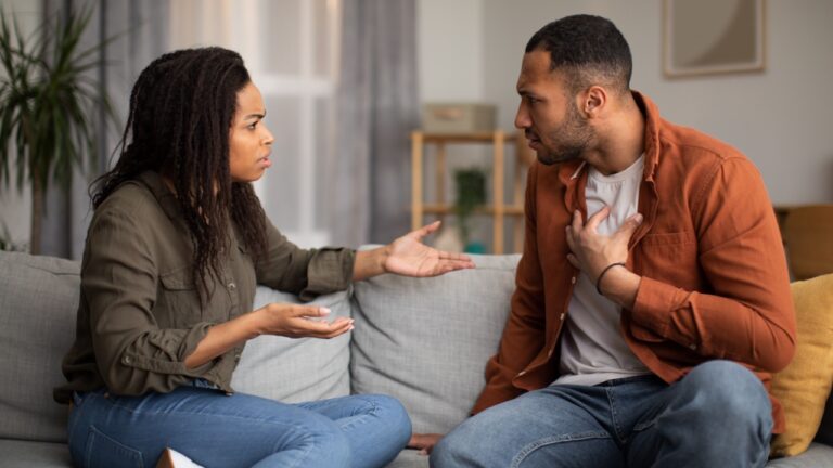 Angry Black Couple Having Quarrel Experiencing Crisis In Relationship Sitting On Sofa At Home. Spouses Having Conflict Breaking Up. Marital Problems.