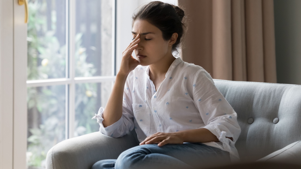Depressed frustrated young Indian woman suffering from headache, migraine, touching face, head with closed eyes, feeling stressed, sick, tired, thinking over bad news, problems, crisis