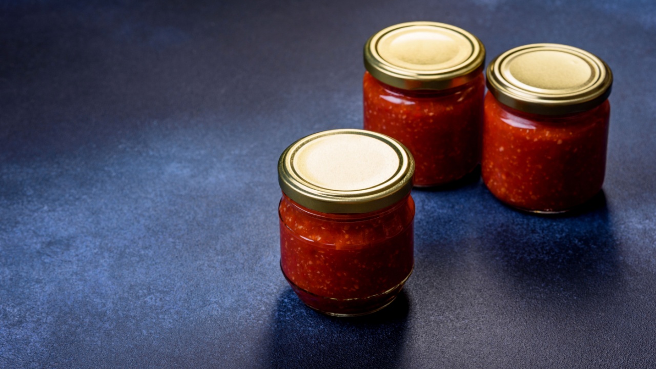 Tomato and chili sauce, jam, confiture in a glass jar on a blue stone background