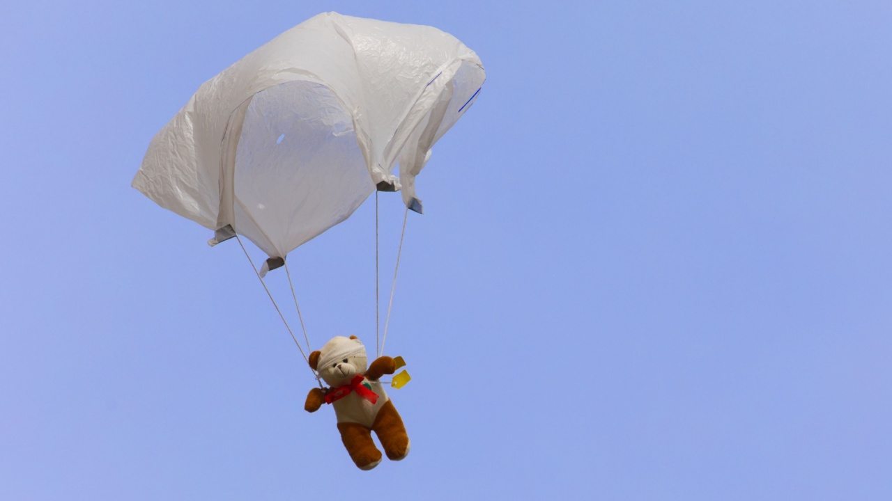 Teddy Bear on a handkerchief parachute against a blue sky, space for copy text, unusual.