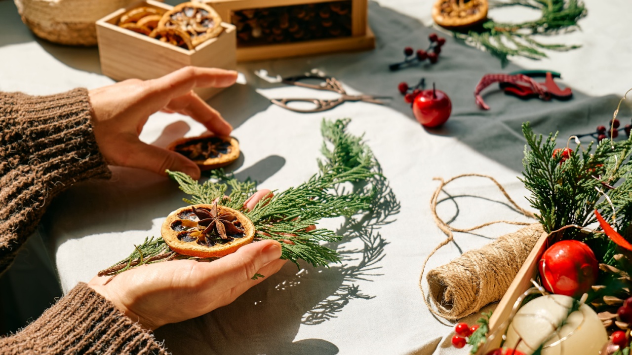 Woman making Christmas arrangement with fir branches and dried oranges. Female hands creating Christmas craft handmade decor. New year celebration. Winter holidays.