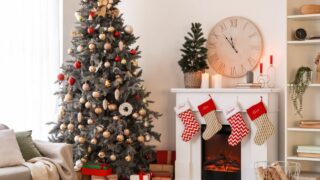 Interior of living room with big clock, fireplace and Christmas trees