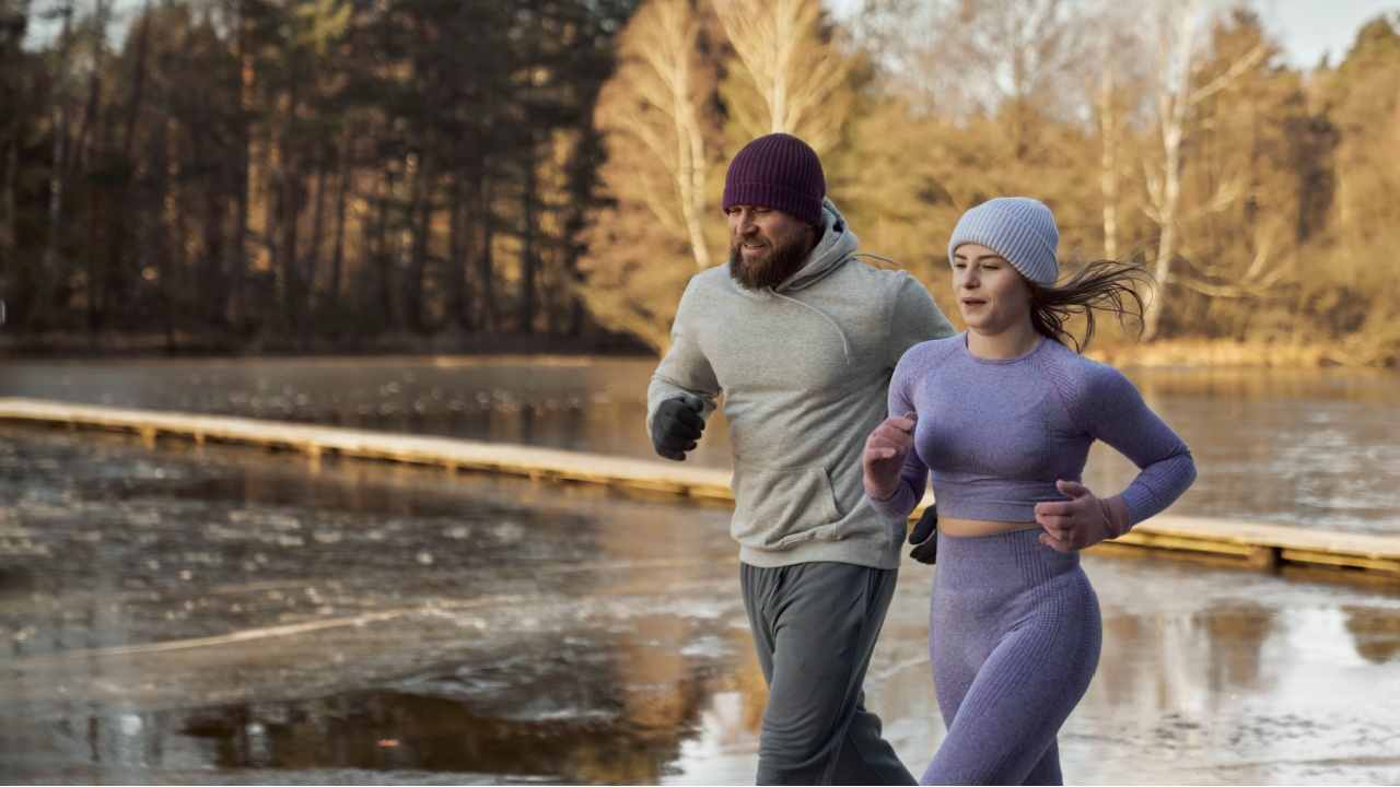 Adult caucasian couple running outdoors in the winter by the lake