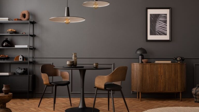 Aesthetic composition of living room interior with mock up poster frame, round black coffee table, wooden sideboard, dark wall with stucco, rug, rack and personal accessories.