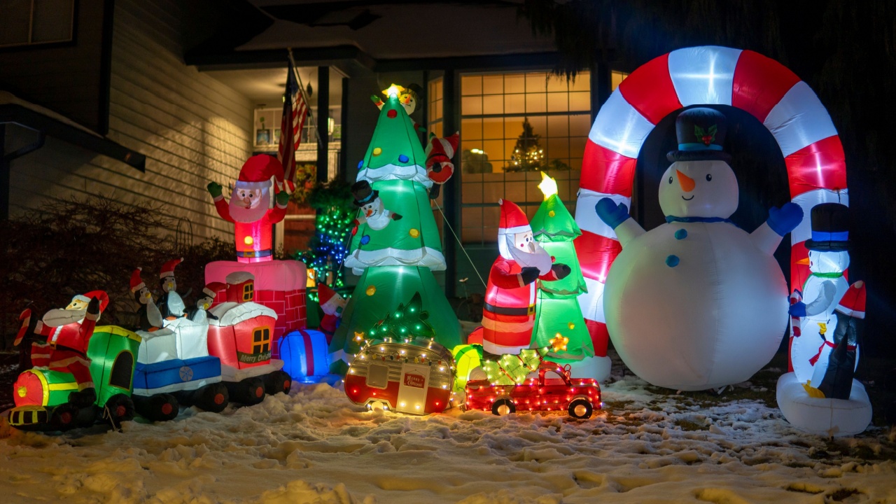 Inflatable figures of snowman, Santa Claus, train and Christmas tree glowing at night. Christmas and New Year holiday decorations. Selective focus, blurred background