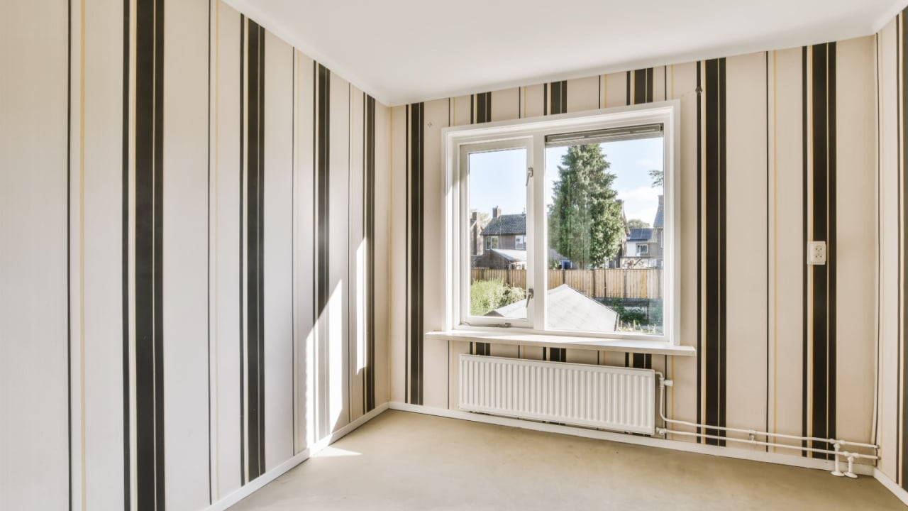 an empty room with striped wallpapers on the walls and large windows in the room is white, beige and black