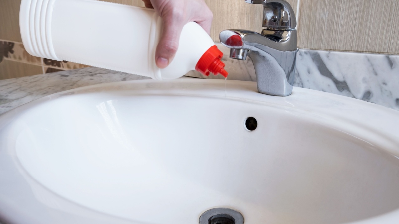Removal of blockage in the sink, the hand of a man with a bottle of a special remedy with granules. Clean the blockages in the bathroom with chemicals. High quality horizontal photo