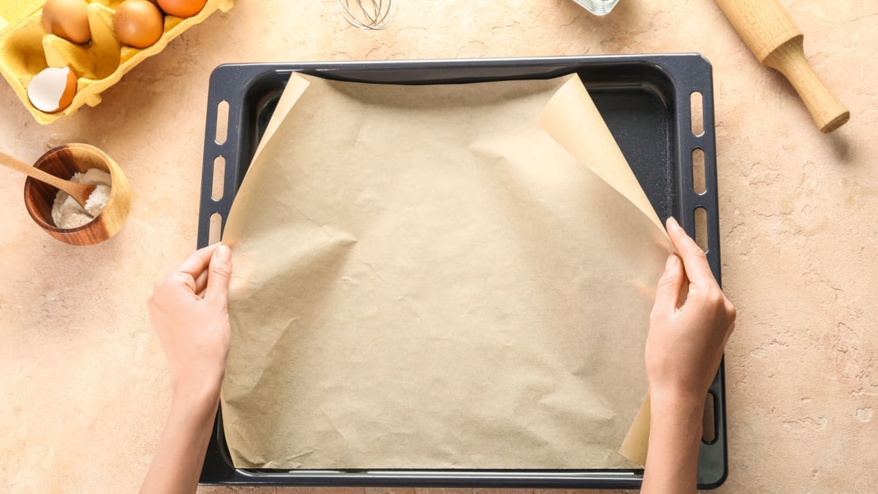 Woman with parchment paper, baking tray and ingredients