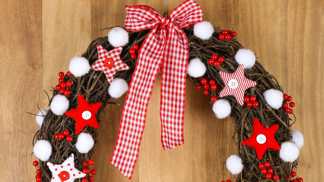 Decorated christmas door wreath with red and white pillow stars with gingham bow brown twigs gingham and polka dot on sapele wood background, copy space