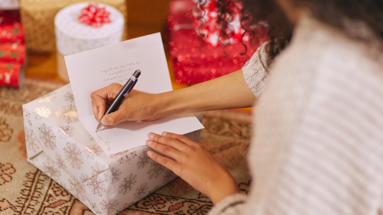 Merry Christmas, all my love. a unrecognisable woman writing a message in a card during Christmas at home.