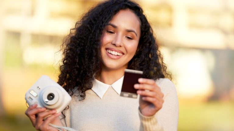 My favourite camera. Shot of a young woman taking a picture with a camera while standing outside.