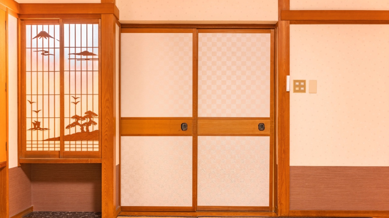 Wall of a typical traditional Japanese room featuring tatami mats covering the floor, fusuma doors and shoji window made of rice paper with wooden decorations evocating a landscape of the mount Fuji.