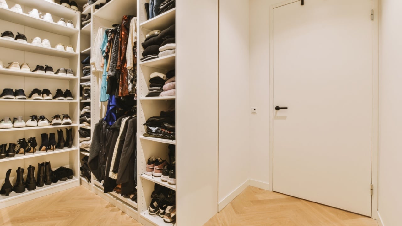 a walk - in closet with lots of shoes on the shelfs and clothes hanging on the wall behind it