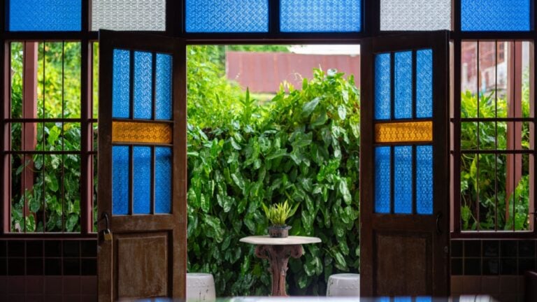 Stained glass of various colors is used to embellish the walls, doors, and windows of the old wooden house