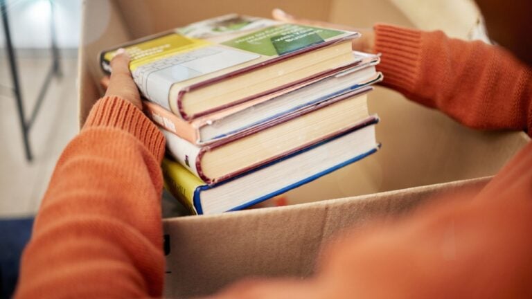 Donation, charity and woman hands with books in box for nonprofit and cardboard container at home. Education textbook, donating and house with giveaway and spring cleaning for community support