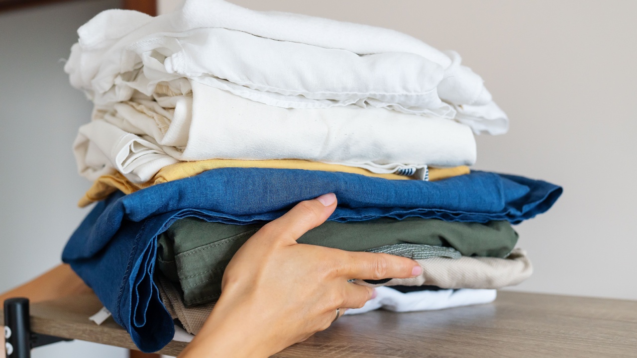 A large pile of clothes after washing, the girl takes the clothes to hide in the closet. Selective focus, noise. Homework