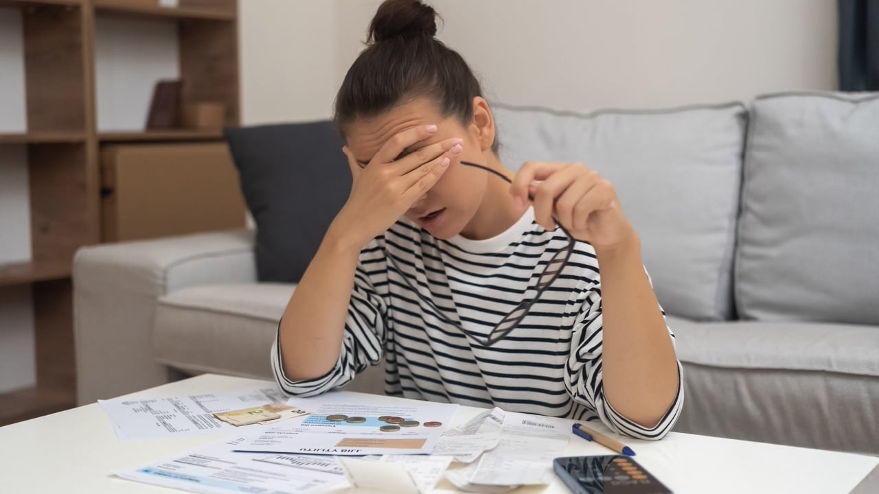Budgetary Woes: Unhappiness looms as a woman wrestles with debt, navigating household finances, and calculating expenses for online payments.