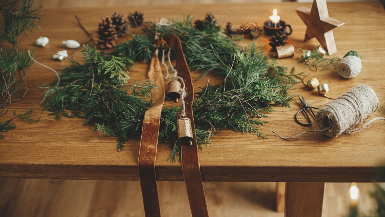 Christmas rustic wreath. Stylish christmas wreath with cedar branches, ribbon, vintage bells, pine cones, scissors on wooden table. Winter holiday preparations, atmospheric time