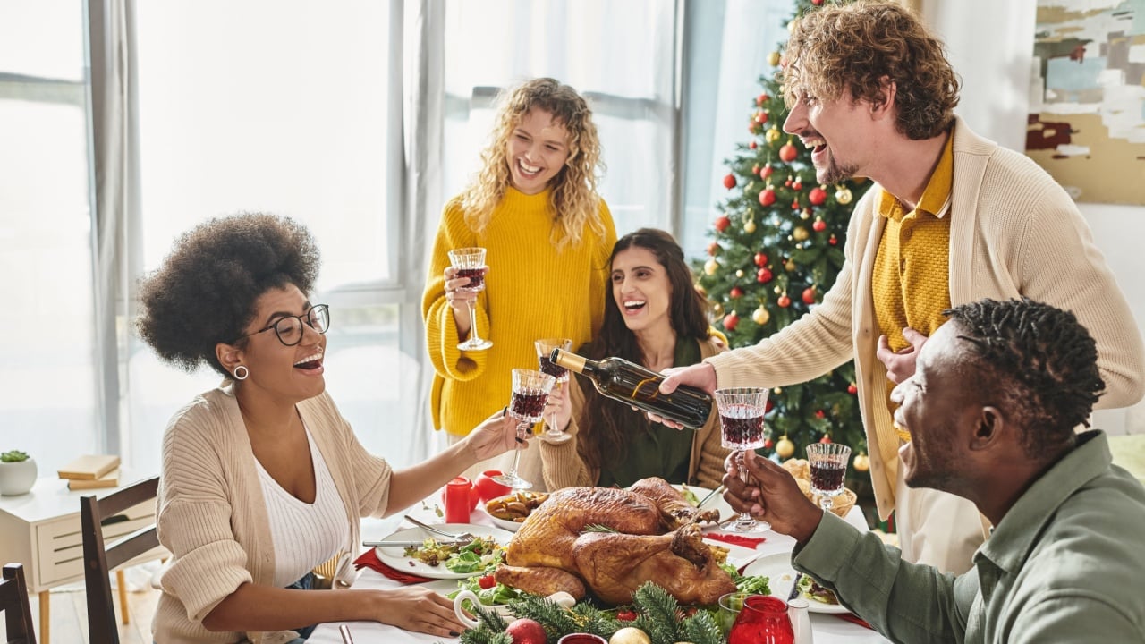 cheerful multiethnic relatives having great time together laughing and drinking wine, Christmas