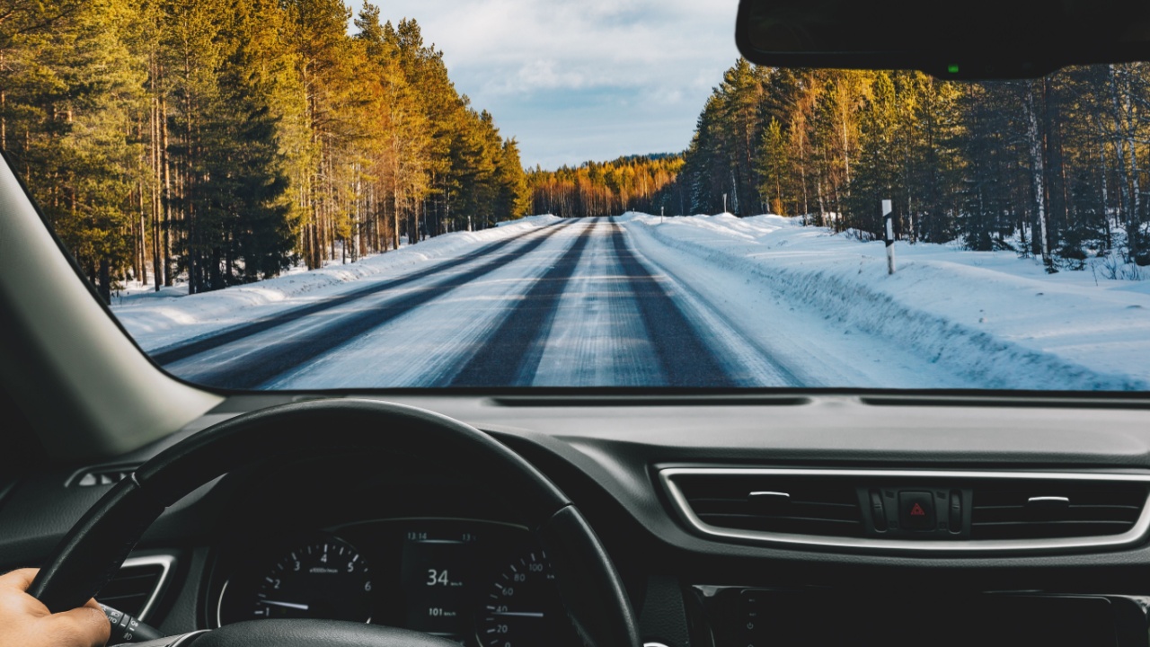 Man driving car on frozen snow country road in winter Finland. Rear view.