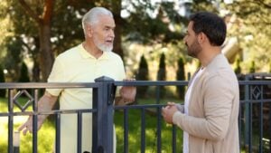 Relationship with neighbours. Men near fence outdoors