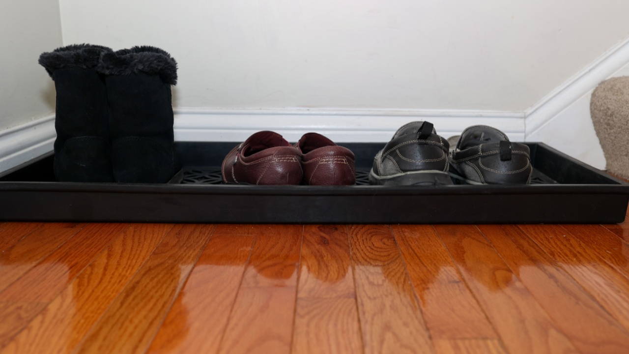 Shoes sitting on a entryway shoe tray by the front door of a home