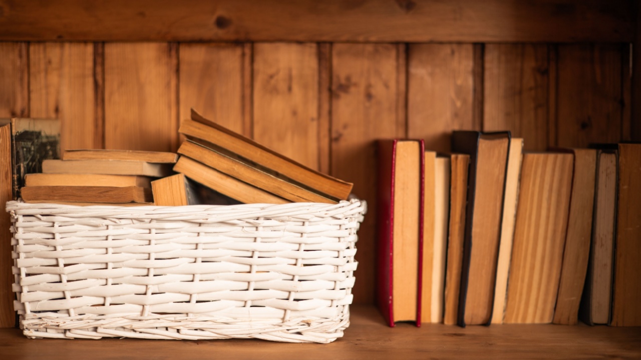 old books kept in a white wicker basket on the library bookcase