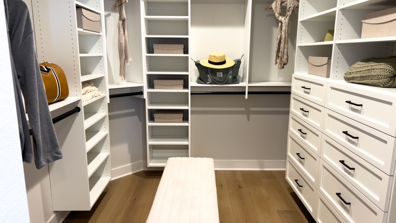 Denver, Colorado, USA-February 29, 2024-Elegantly organized walk-in closet showcasing custom white shelving full of neatly arranged clothes and accessories, with a central ottoman providing