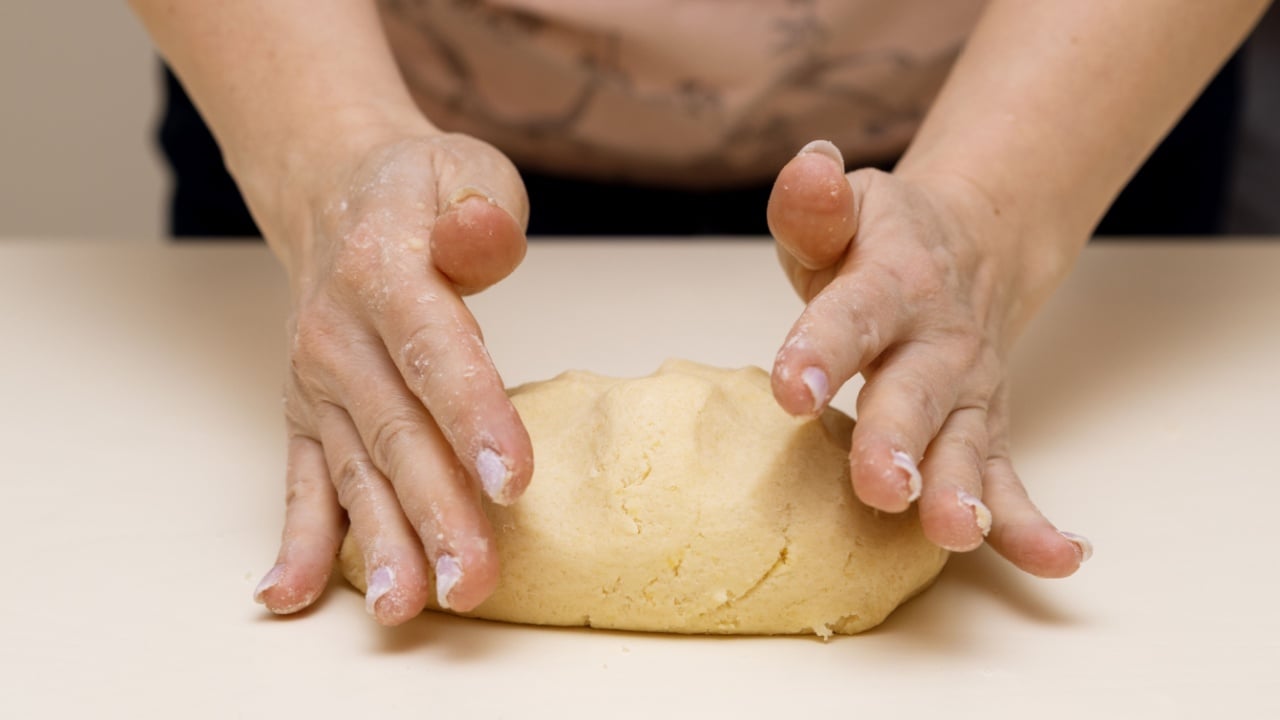 Women's hands knead the dough for making shortbread cookies
