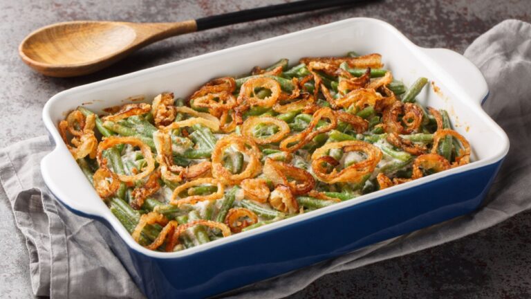 Green bean casserole with cheesy mushroom sauce and topped with crispy onions close-up in a baking dish on the table. horizontal